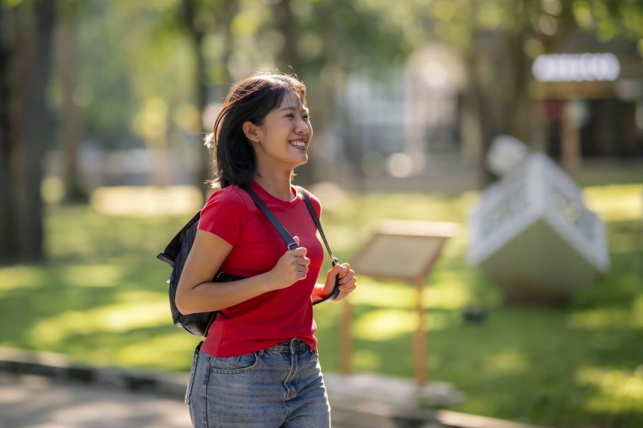 Asian woman walking through a park with a smile on her face